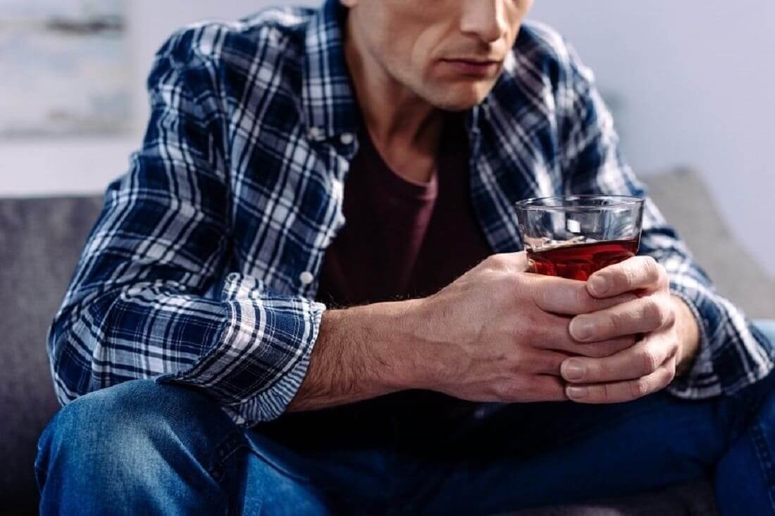 Мужчина держит стакан с алкоголем в руке